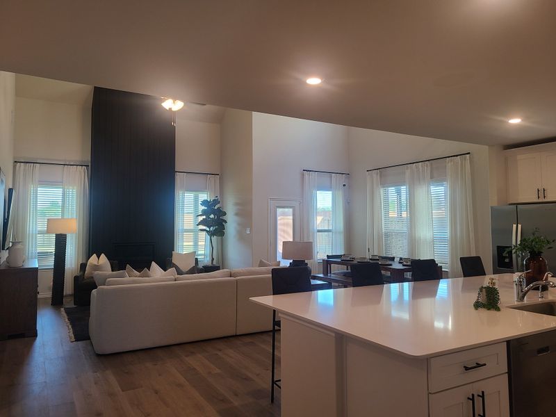 An open living space with a sleek kitchen, cozy seating, large windows, and modern decor.