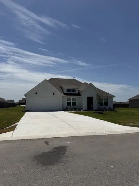 A modern white home with a large driveway in Hartland Ranch by D.R. Horton (Lockhart, TX).