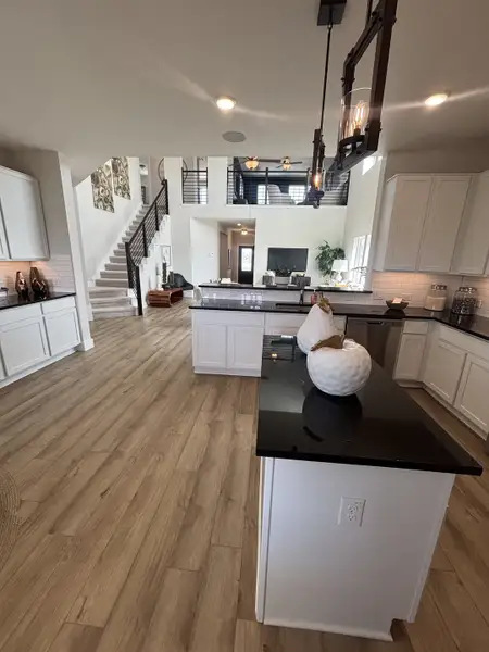 A spacious open-concept kitchen with black countertops, white cabinetry, and a stunning view of the lofted living space. A spacious open-concept kitchen with black countertops, white cabinetry, and a stunning view of the lofted living space.