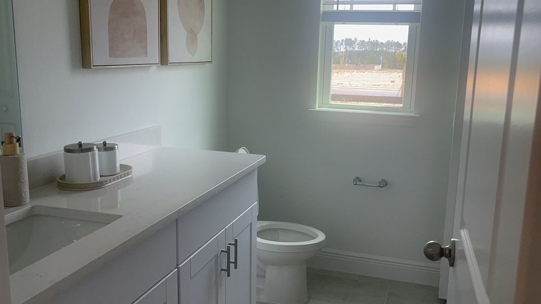 A bright bathroom with a sleek white vanity, minimalist decor, large window, and modern fixtures creating a serene atmosphere.