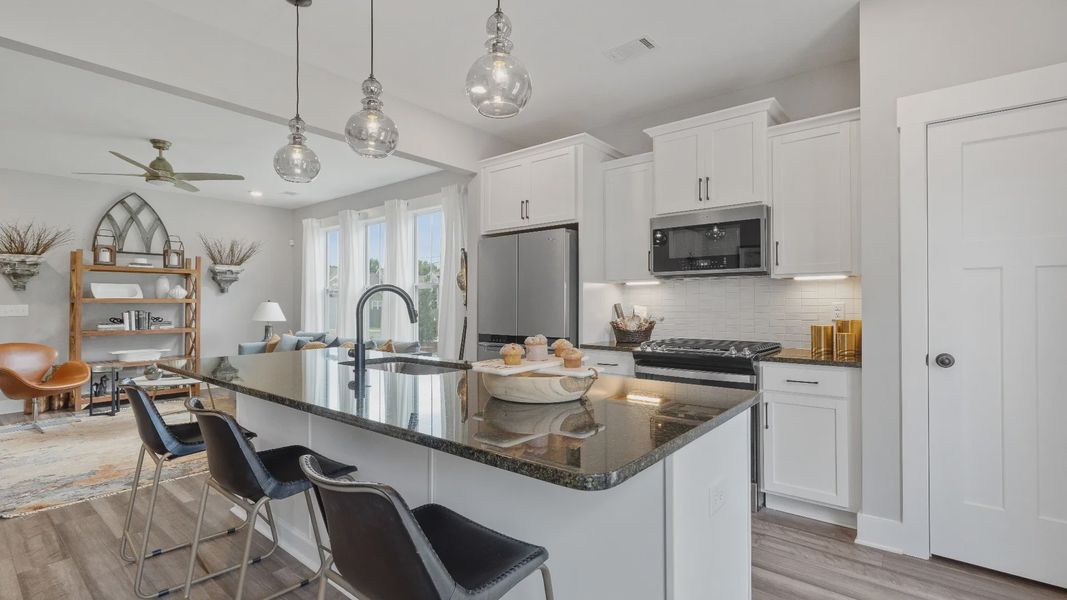 White cabinetry kitchen with modern pendant lighting and granite countertops at Barton Hollow in Fountain Inn, SC