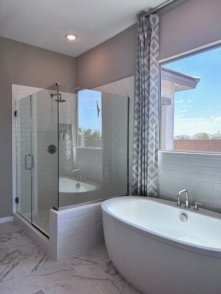 A luxurious bathroom features a modern glass shower, elegant soaking tub, and patterned drapes for a serene ambiance. A luxurious bathroom features a modern glass shower, elegant soaking tub, and patterned drapes for a serene ambiance.