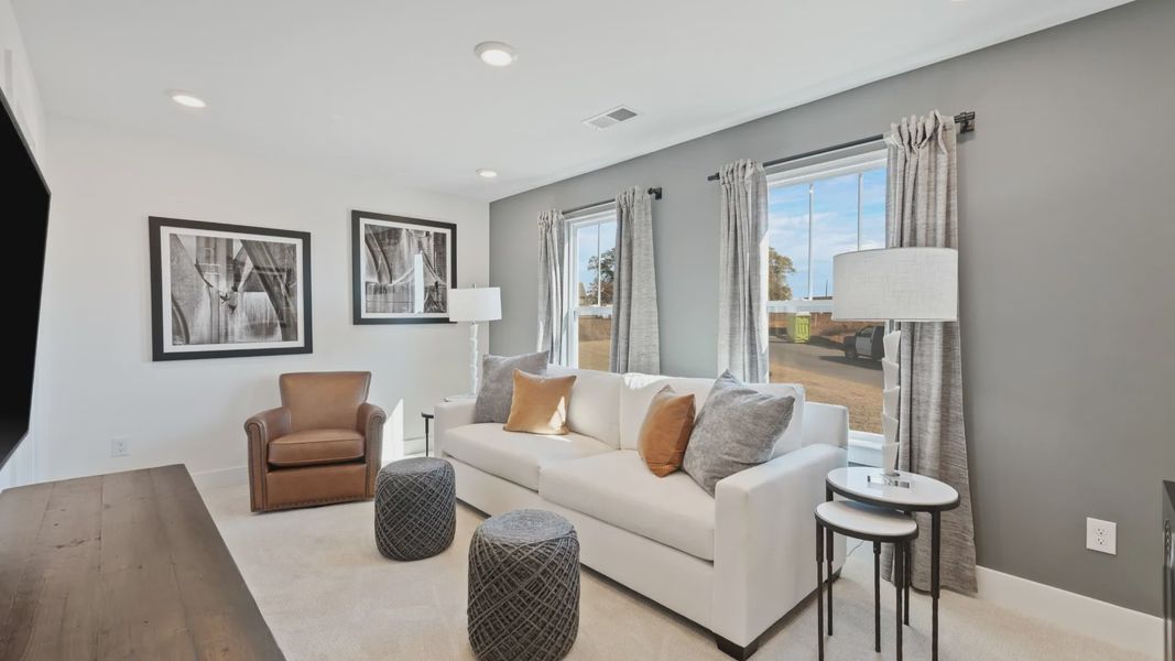 Carpeted secondary bedroom with modern accent wall, tall ceilings, and boasting windows at Pleasant Falls by DRB Homes