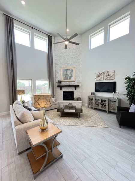 A bright, modern living room with high windows, a stone accent wall, and sleek furnishings.