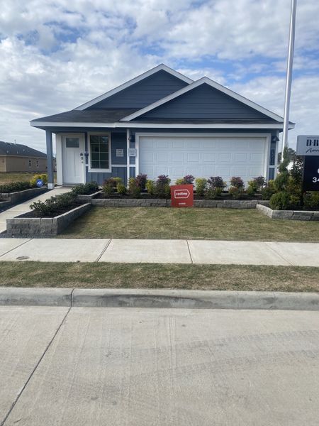 A charming navy blue home with white trim and a landscaped front yard in Heritage Crossing by D.R. Horton (Houston, TX).