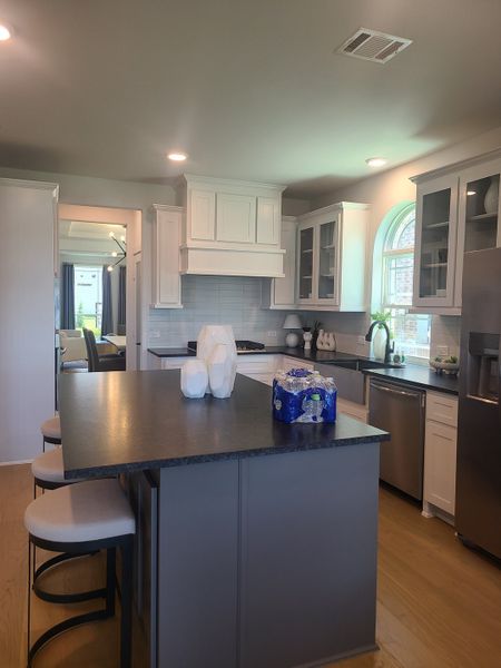 A modern kitchen with sleek black countertops, white cabinetry, and stainless steel appliances.