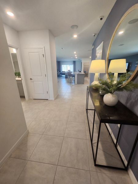 A bright hallway with tiled flooring, a console table, and decorative elements leading to a spacious, inviting living area.