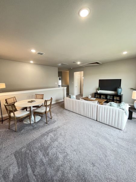 An inviting living area with plush carpeting, cozy white seating, a sleek dining set, and ambient lighting.