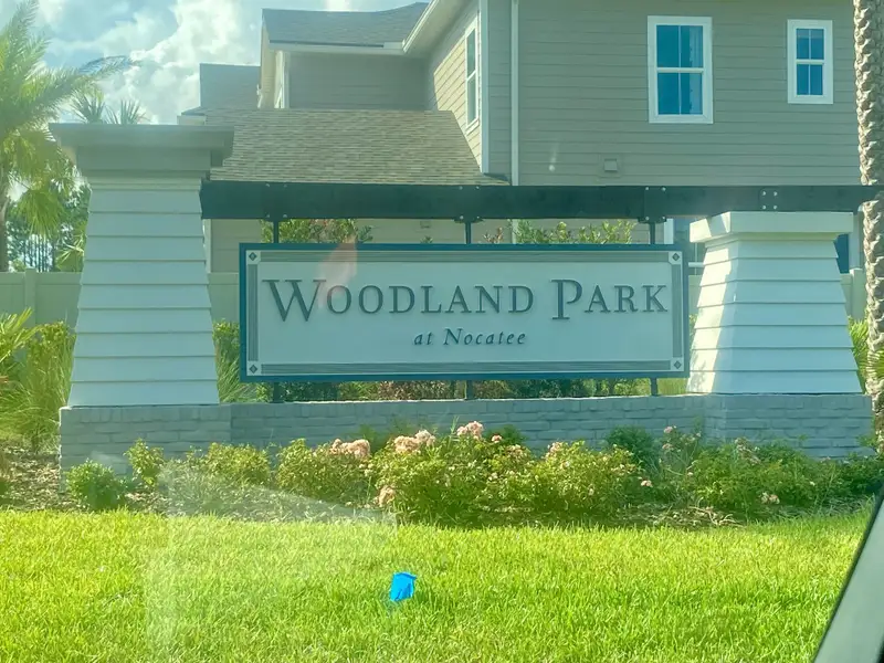 A welcoming entrance to Woodland Park by Providence Homes in Ponte Vedra Beach, FL, featuring lush landscaping.