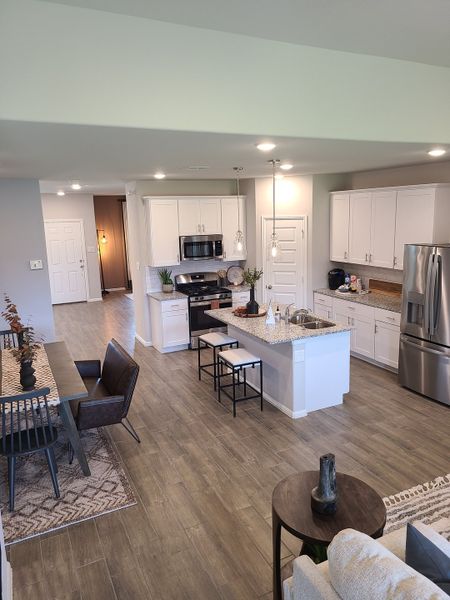 A modern kitchen with sleek white cabinets, an island with bar stools, and an open-concept dining area with stylish decor.