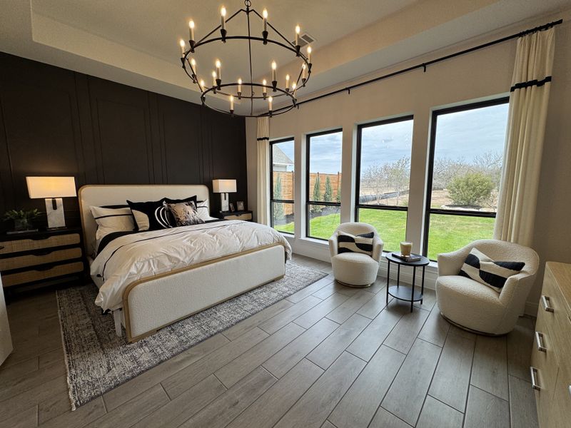 A spacious bedroom featuring a luxurious bed, chic chandelier, elegant black accent wall, and large windows opening to a scenic view. A spacious bedroom featuring a luxurious bed, chic chandelier, elegant black accent wall, and large windows opening to a scenic view.