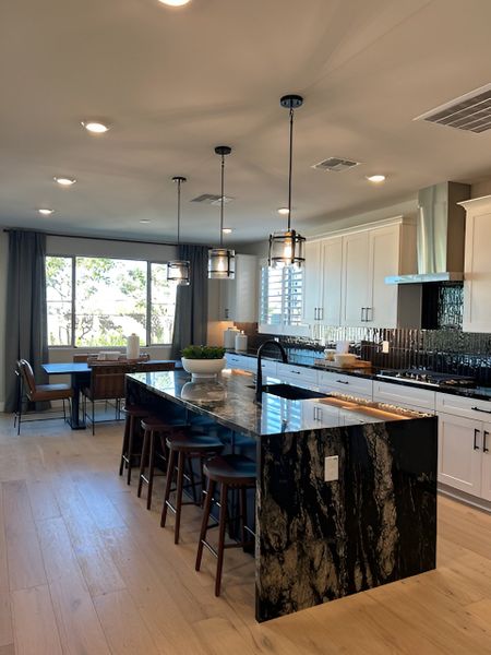 A contemporary kitchen featuring a bold black marble island, white cabinetry, and stylish pendant lighting.