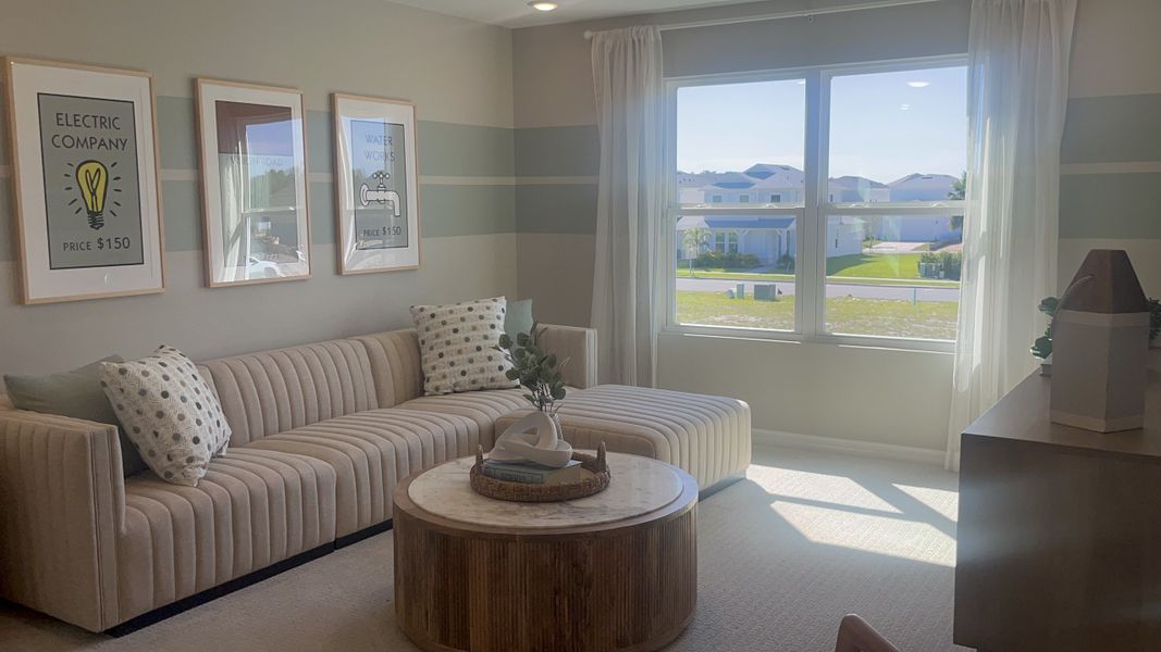 A cozy living room with a striped sofa, modern art, and a round wooden coffee table by a large window.