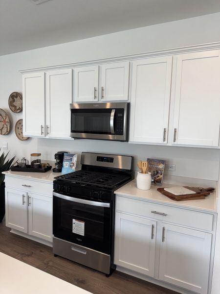 A modern kitchen featuring sleek white cabinets, stainless steel appliances, and elegant decor accents.