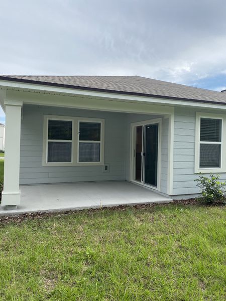 A charming patio with sliding doors and a grassy yard in Wells Landing by Centex (Jacksonville, FL).
