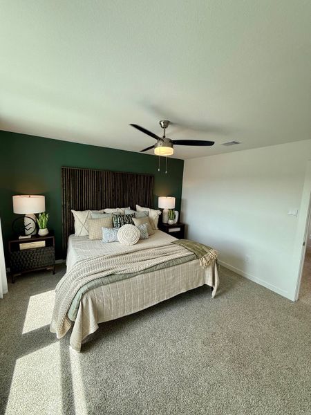 A cozy bedroom with a deep green accent wall, plush bedding, and stylish lamps, creating a serene retreat.