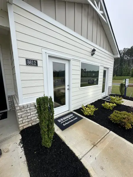 Charming light beige home in Champion's Run by D.R. Horton with sleek landscaping and welcoming entrance (Lithonia, GA).