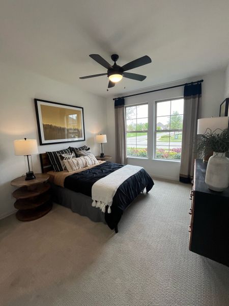 A cozy bedroom with modern ceiling fan, large window, neutral tones, and chic decor.