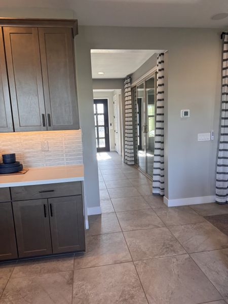 A modern hallway with tiled floors, dark wood cabinetry, and neutral tones, accented by striped curtains and sleek fixtures. A modern hallway with tiled floors, dark wood cabinetry, and neutral tones, accented by striped curtains and sleek fixtures.