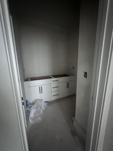 A room under construction with white cabinets and unfinished flooring, showcasing potential for customization.