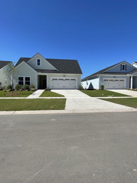 A charming white home with a lush yard in Horizons at Carnes Crossroads | 55+: Legends Collection by Lennar (Summerville, SC).