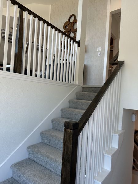 A modern staircase with soft carpeting, sleek white railings, and a decorative wall accent for a stylish interior. A modern staircase with soft carpeting, sleek white railings, and a decorative wall accent for a stylish interior.