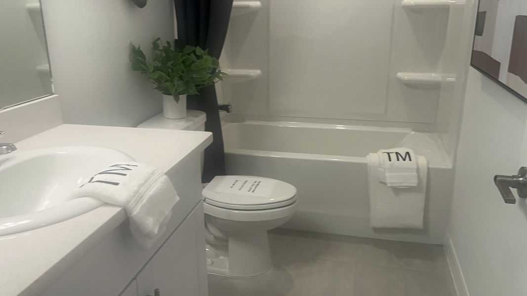 A sleek bathroom featuring a pristine white tub, modern vanity, and decorative greenery for a refreshing appeal.
