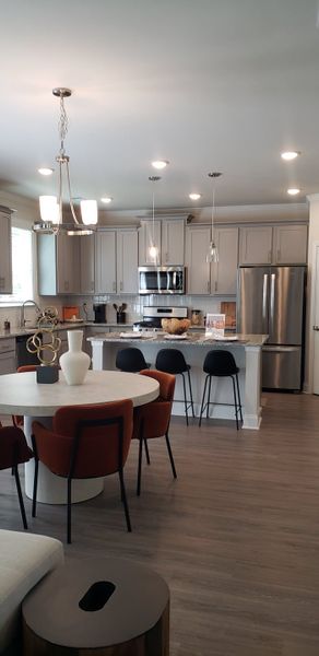 A modern kitchen features sleek gray cabinets, a chic island, and a cozy dining area with stylish lighting.
