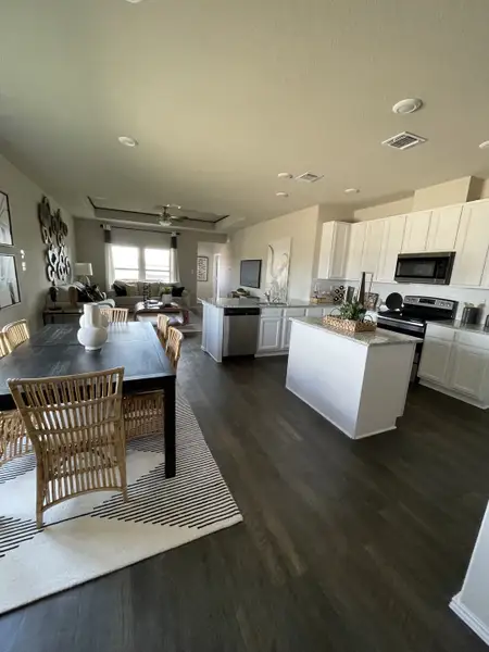 An open-concept kitchen and dining area with sleek counters, modern appliances, and natural woven chairs.