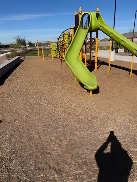 Charming community playground with a vibrant green slide at McClellan Ranch - Reserve Series by Meritage Homes (Laveen, AZ).