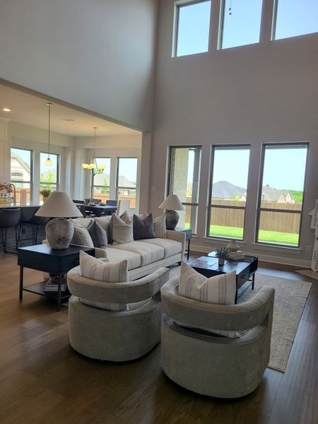 A spacious living area with high ceilings, cozy seating, and ample natural light through large windows.