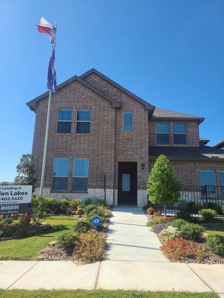 A beautiful brown brick home with a manicured garden in The Landing at Hidden Lakes by D.R. Horton (McKinney, TX).