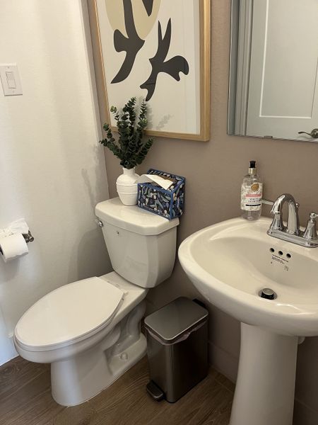 A modern bathroom with sleek fixtures, abstract art, and polished wood flooring for a stylish, functional space.