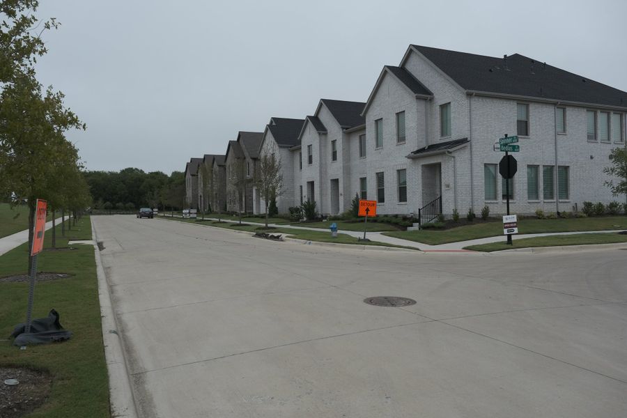 A row of elegant modern homes lines a quiet street in Painted Tree - Village District by CB JENI Homes (McKinney, TX). A row of elegant modern homes lines a quiet street in Painted Tree - Village District by CB JENI Homes (McKinney, TX).