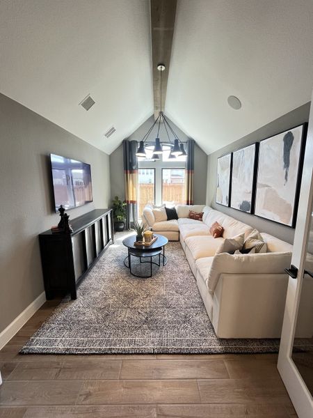 A cozy living room with vaulted ceilings, stylish lighting, a large sectional, and modern decor accents. A cozy living room with vaulted ceilings, stylish lighting, a large sectional, and modern decor accents.