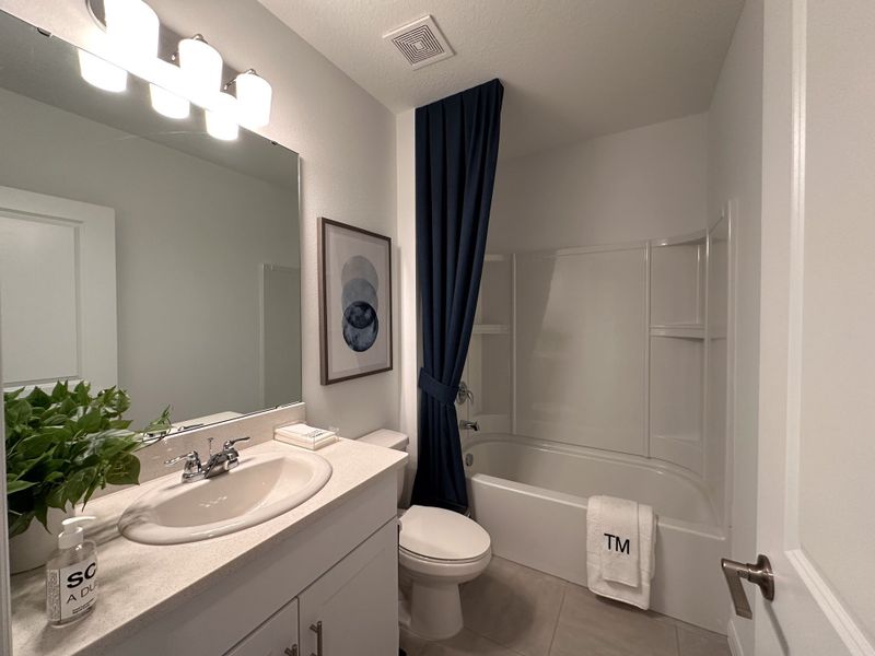 A modern bathroom featuring a sleek vanity, elegant lighting, and a sophisticated blue shower curtain.