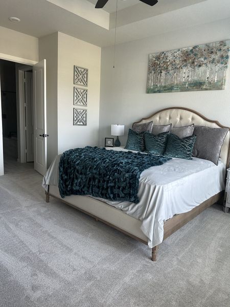 A cozy bedroom with a tufted headboard, plush teal accents, and elegant wall art, offering a serene and inviting atmosphere.