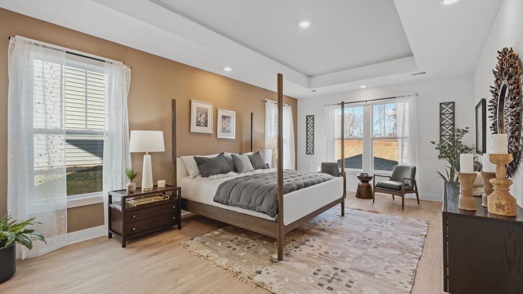 Spacious primary suite elevated by hardwood flooring, vaulted ceilings, and large windows at Fox Hollow in Spartanburg, SC