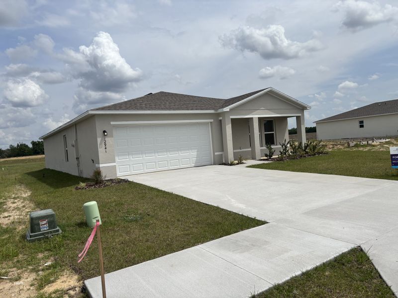 A modern single-story home with a neatly manicured lawn in Bennah Oaks by Century Complete (Belleview, FL).