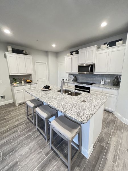 A modern kitchen featuring white cabinets, granite countertops, and a sleek island with bar seating. A modern kitchen featuring white cabinets, granite countertops, and a sleek island with bar seating.