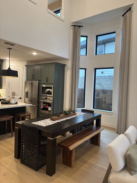 A contemporary dining area with a sleek black table, wicker chairs, and high ceilings, featuring large windows and light wood flooring. A contemporary dining area with a sleek black table, wicker chairs, and high ceilings, featuring large windows and light wood flooring.