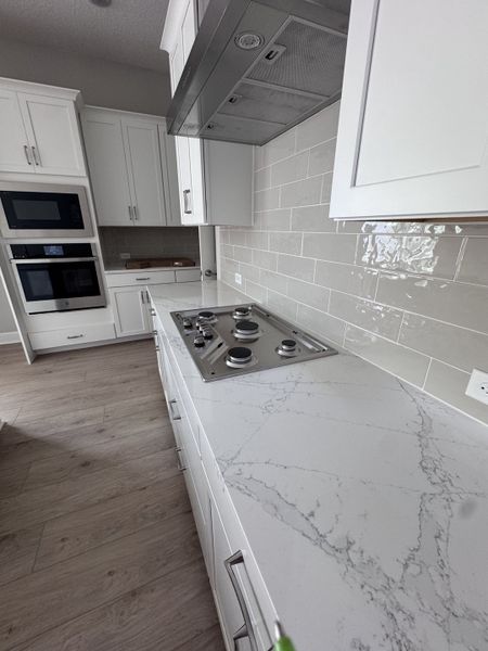 A modern kitchen with sleek white cabinetry, marble countertops, and stainless steel appliances. A modern kitchen with sleek white cabinetry, marble countertops, and stainless steel appliances.