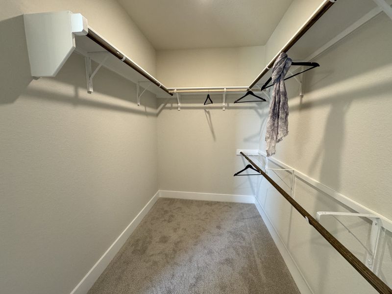 A spacious walk-in closet with plush carpeting, hanging rods, and ample storage opportunities.