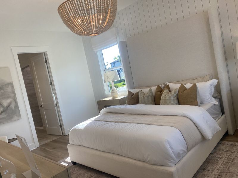 A cozy bedroom with a plush bed, elegant pendant light, and soft natural tones, creating a serene ambiance.