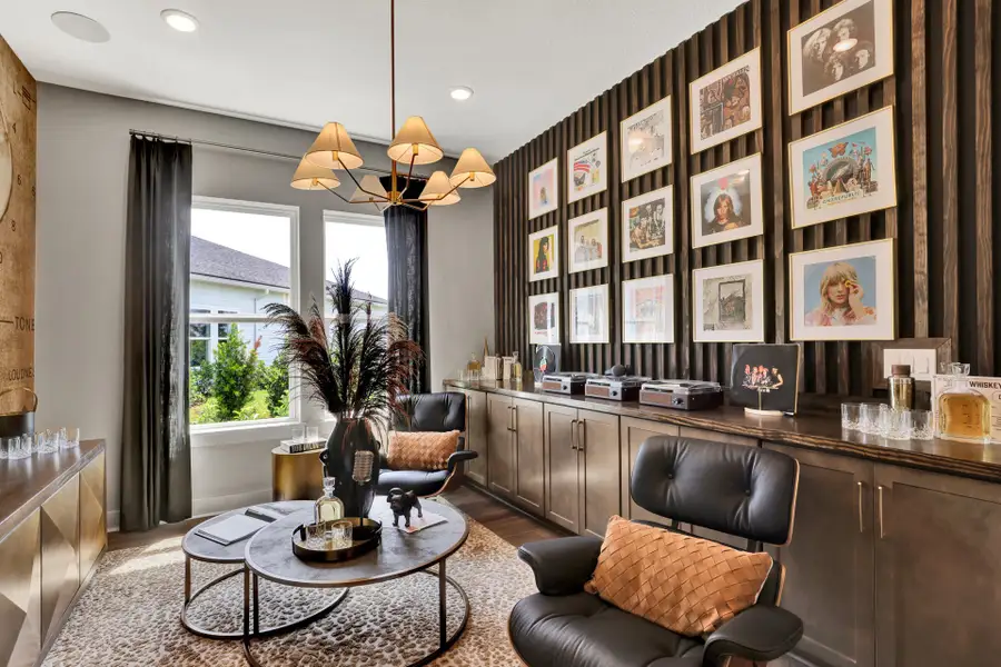 Music-themed lounge with framed vinyl album covers on dark accent wall, leather chairs, and built-in cabinets Music-themed lounge with framed vinyl album covers on dark accent wall, leather chairs, and built-in cabinets