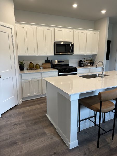A modern kitchen with sleek white cabinets, stainless appliances, and a large island with seating.