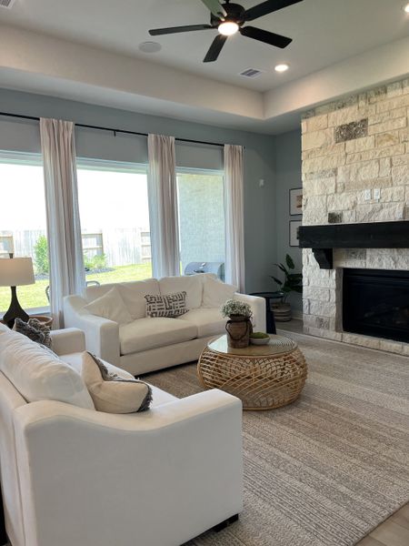 A cozy living room featuring white sofas, a woven coffee table, and a stone fireplace with large windows for natural light. A cozy living room featuring white sofas, a woven coffee table, and a stone fireplace with large windows for natural light.