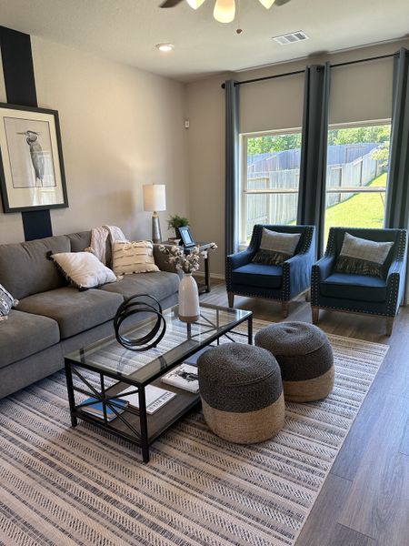 A cozy living room with modern furniture, decorative accents, and large windows overlooking a fenced backyard.