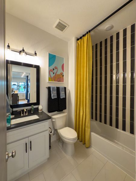 A modern bathroom featuring striped shower tiles, a bright yellow curtain, and sleek vanity with stylish decor. A modern bathroom featuring striped shower tiles, a bright yellow curtain, and sleek vanity with stylish decor.