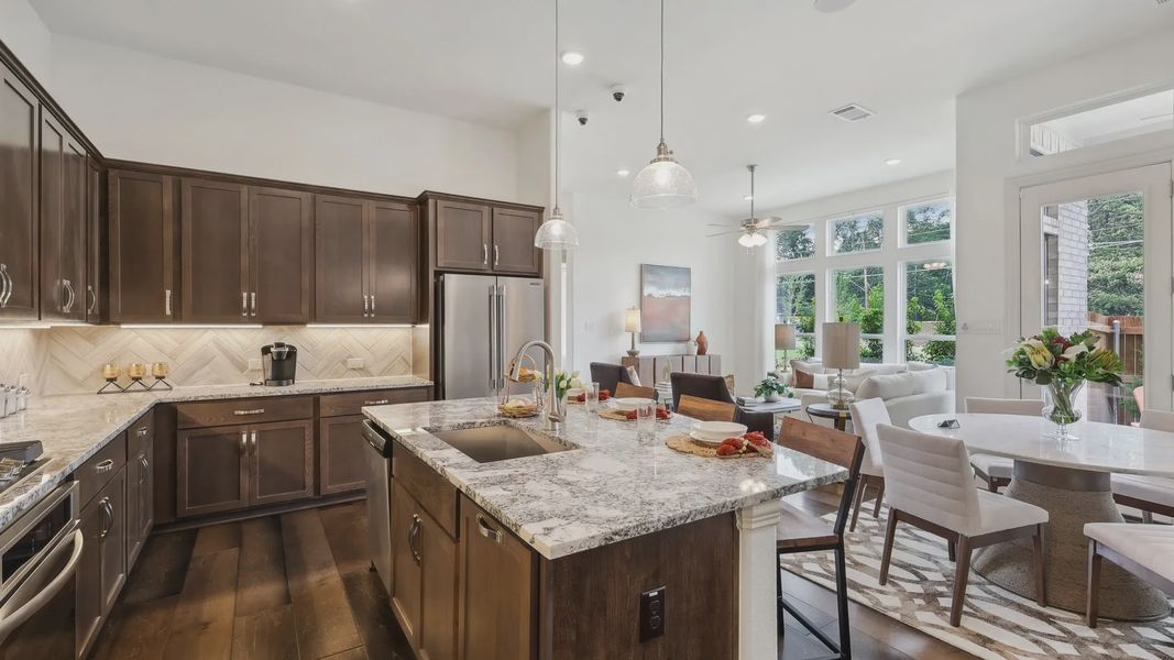 Granite countertops, dark wood cabinetry, and an open floor plan define this Heritage Park luxury kitchen.